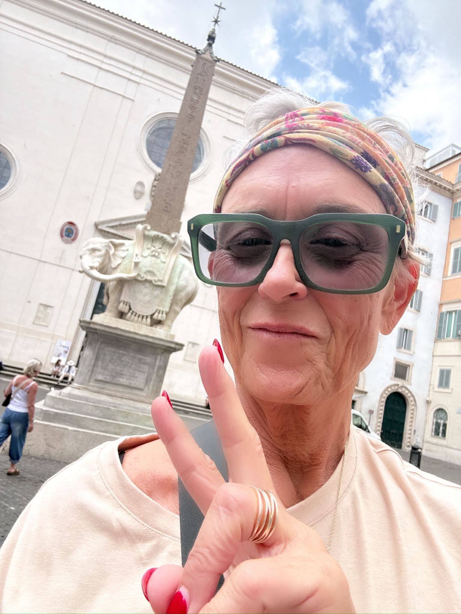 Woman in green glasses making a peace sign before the Elephant and Obelisk in Rome.